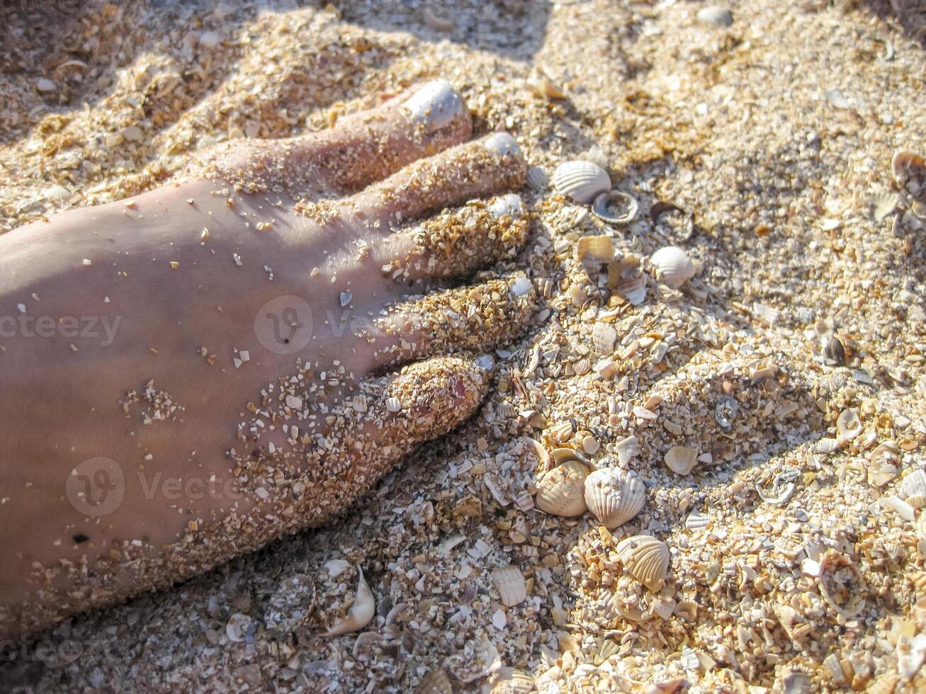 Damen Fuß mit gemalt Silber Fingernägel. Bein Stehen auf das Sand. Pediküre foto