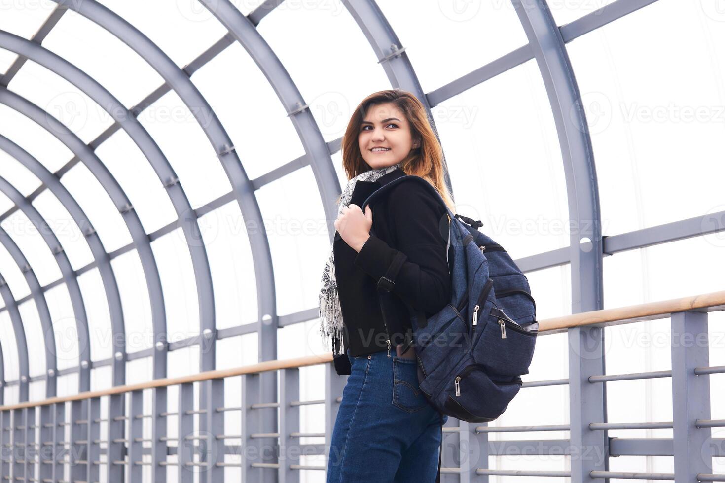 jung schön Frau sieht aus zurück Gehen entlang das bedeckt Überführung foto