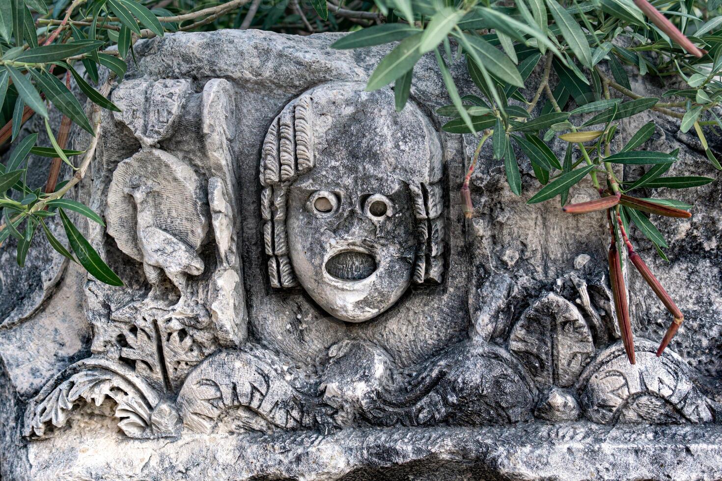 Antiquität Stein gemeißelt Maske unter tropisch Vegetation im das Ruinen von das uralt Stadt von Myra, Truthahn foto