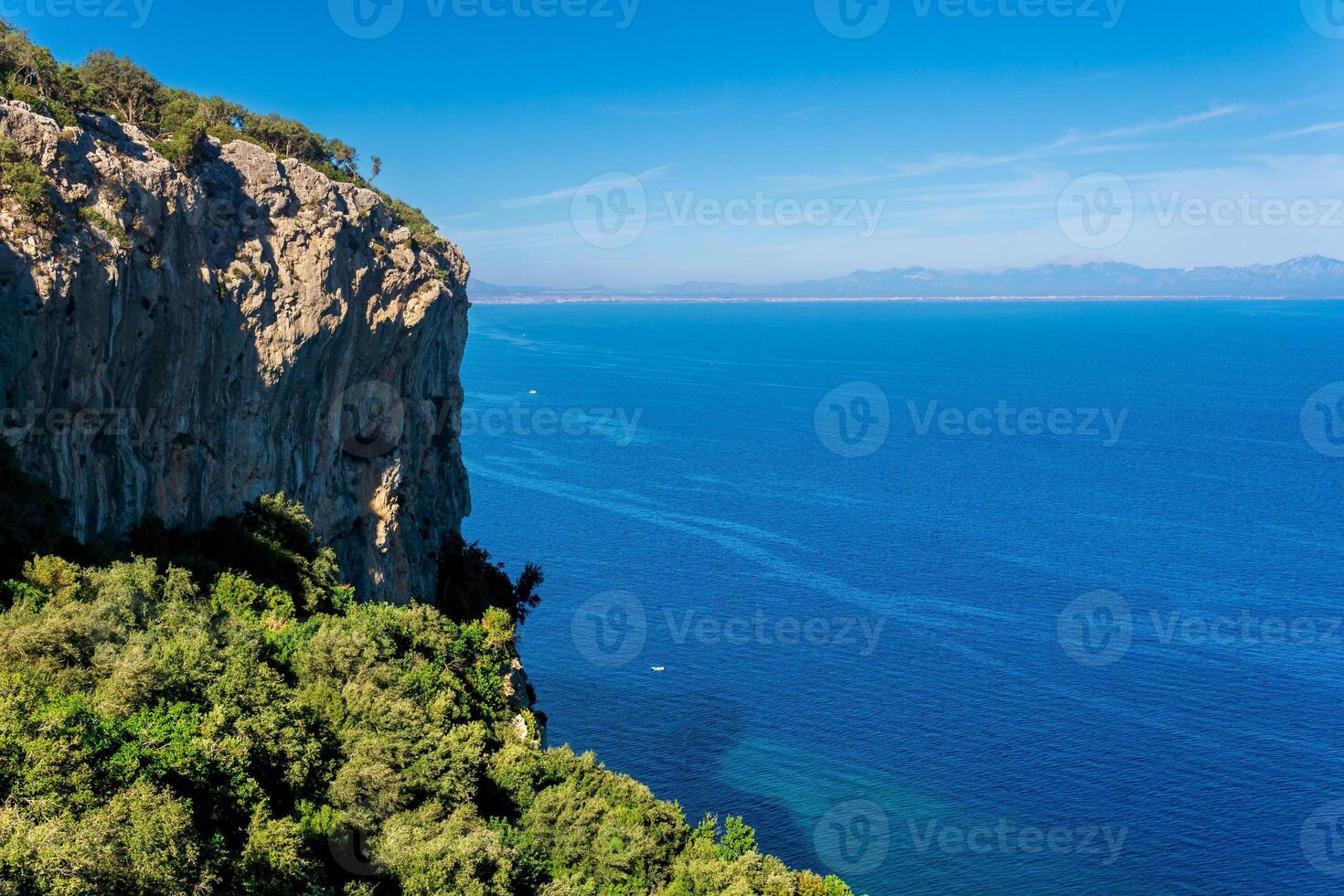 Seelandschaft - - Küsten Klippen im üppig tropisch Vegetation und Blau Meer mit entfernt bergig Ufer foto