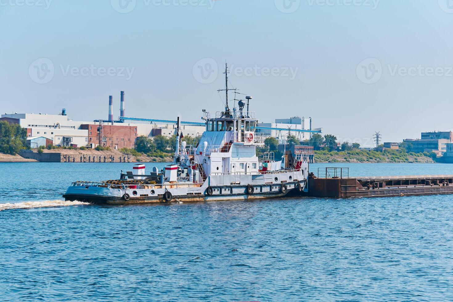 Schleppboot schiebt trocken Bulk Ladung Lastkahn auf das Fluss Vergangenheit das industriell Landschaft foto
