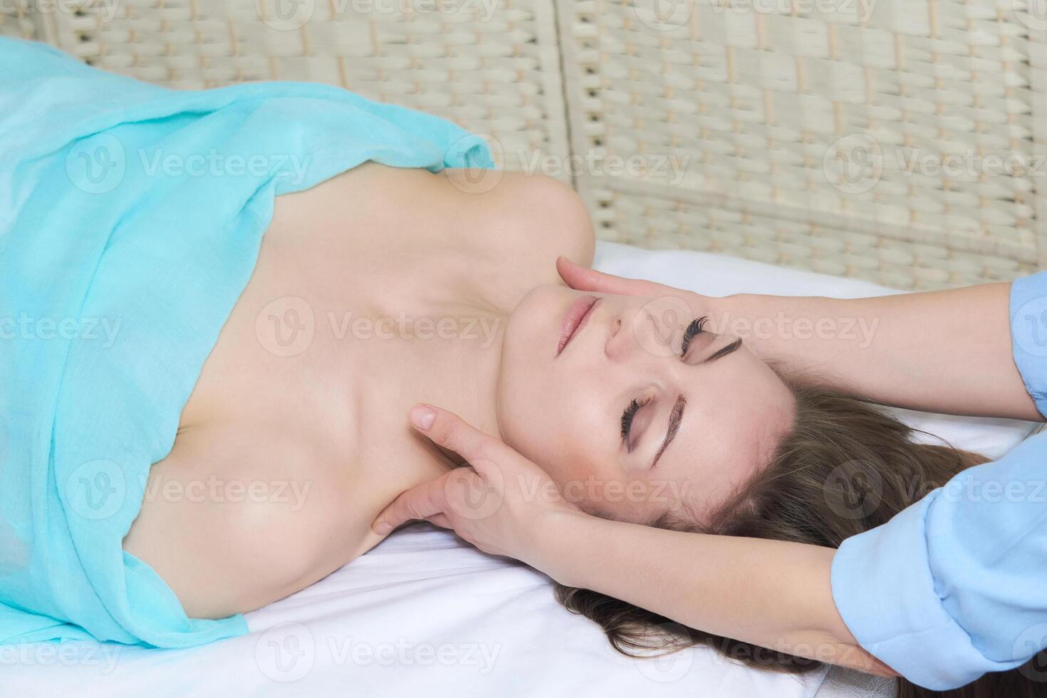 schön jung Frau genießen ein Massage von das Gesicht und Hals Bereich im das Spa Salon foto