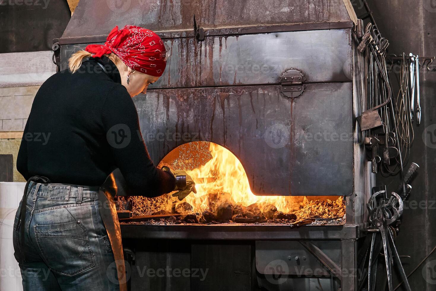 Frau Schmied in der Nähe von ein flammend Schmiede Ofen foto