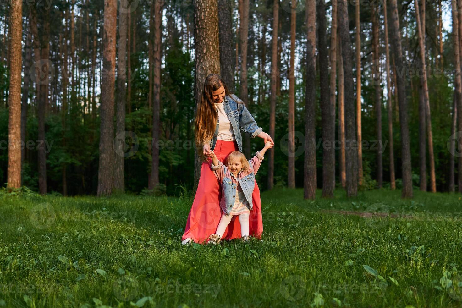 Frau mit wenig Tochter tanzen auf das Rasen im das Park foto