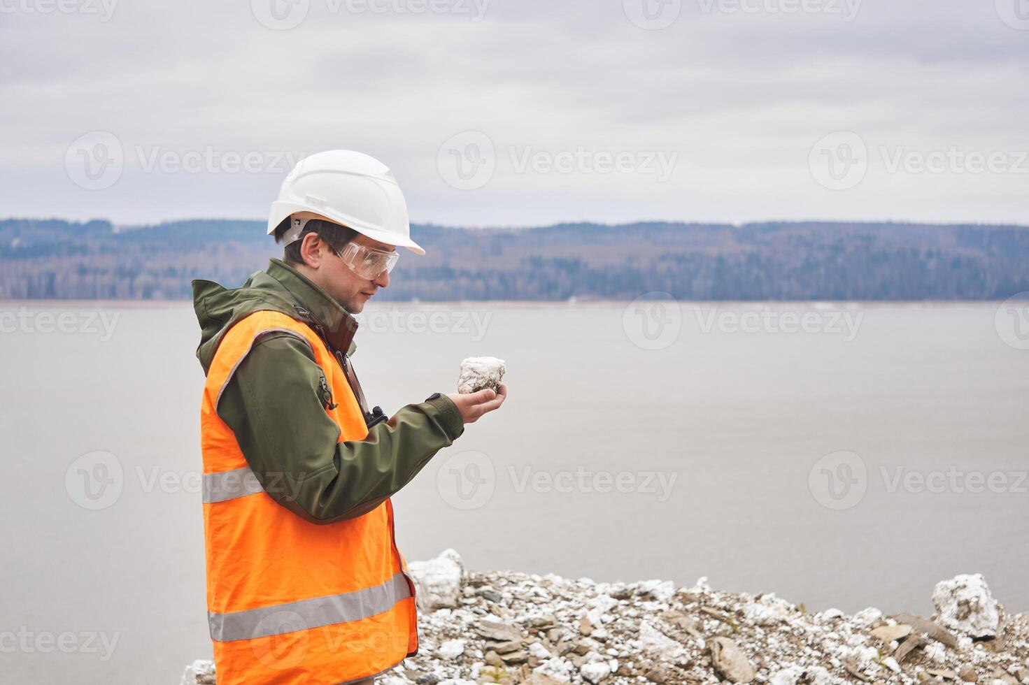 Geologe oder Bergbau Ingenieur untersucht ein Stichprobe von ein Mineral von ein Talus auf ein Fluss Bank foto
