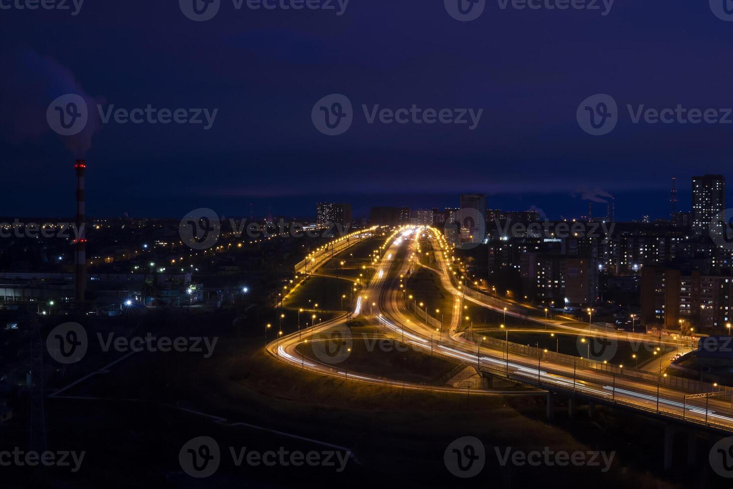 Nacht Stadt Landschaft mit beleuchtet Straße Kreuzung, industriell und Wohn Gebäude foto