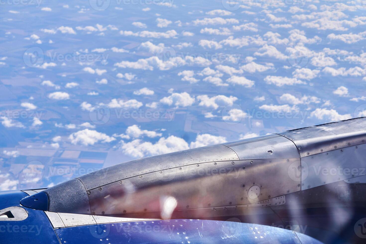 Aussicht von das Fenster von Flugzeug mit verschwommen Highlights auf das Glas, ein Fragment von das Motor, Erde und Wolken ist sichtbar foto