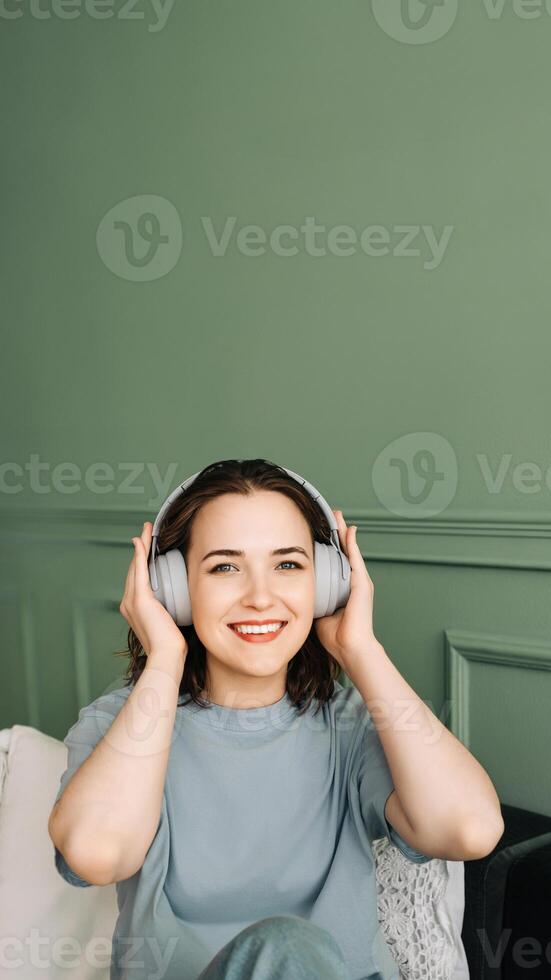 Wochenende fliehen. Erfreut Frau absorbiert im Musical Gelassenheit. Zufriedenheit im Melodien. jung Frau finden Freude im Sofa Musik- Session foto