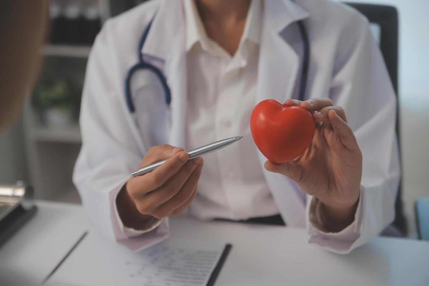 Hände von Arzt Frau halten rot Herz, zeigen Symbol von Liebe, Mensch Unterstützung zu geduldig, fördern medizinisch Versicherung, früh Untersuchung zum Gesundheitspflege, Kardiologe Hilfe. schließen oben von Objekt foto