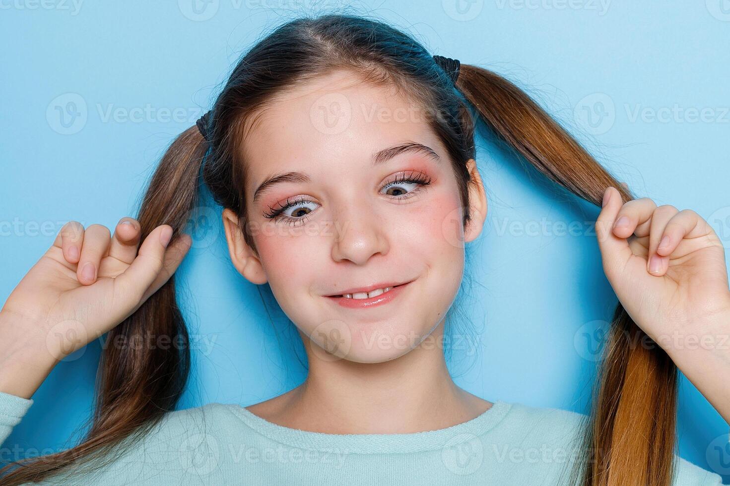 wenig Mädchen verzog das Gesicht und haben Spaß beim Kamera isoliert Über Blau Hintergrund. foto