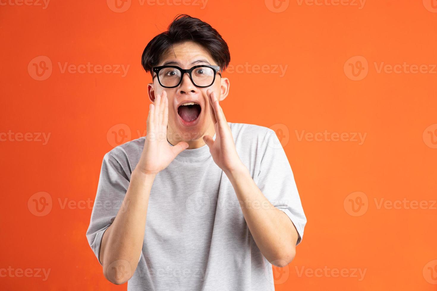 Porträt eines jungen asiatischen Mannes, der fröhlich schreit, isoliert auf orangefarbenem Hintergrund foto