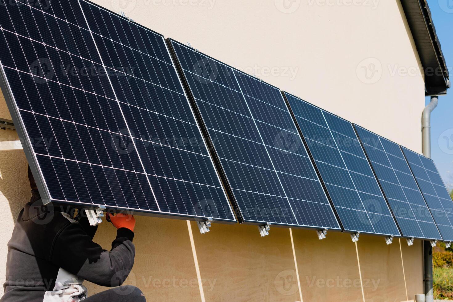 Solar- Paneele auf ein gut belichtet Mauer von ein Individuell Haus, Herstellung Ersparnisse folgenden das Energie Krise, Öko-Bürger Geste, Grün Energie foto