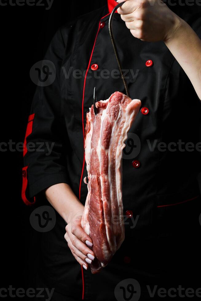 ein Stück von Schweinefleisch Bauch Fleisch. das Koch bereitet vor Speck Porchetta. auf ein schwarz Hintergrund. foto