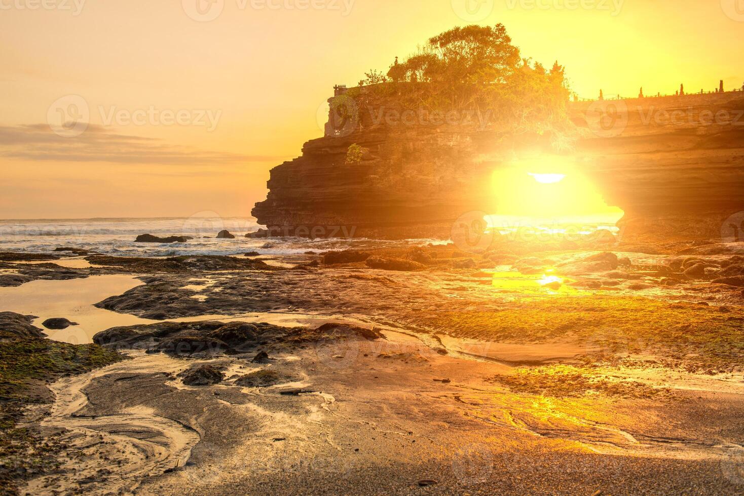 schön Sonnenuntergang Aussicht aussehen durch Bogen Felsen unten pura batu bolong ein ikonisch Hinduismus Meer Tempel im bali Insel von Indonesien. foto