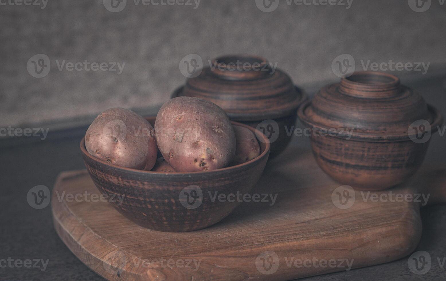 Kartoffeln im ein braun Teller und zwei Lehm Töpfe. filmisch foto