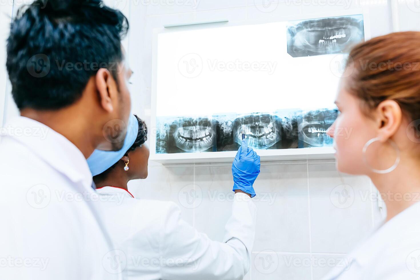 gemischtrassig Dental Mannschaft Überprüfung Zähne x Strahl von geduldig. Dental Klinik Konzept. foto