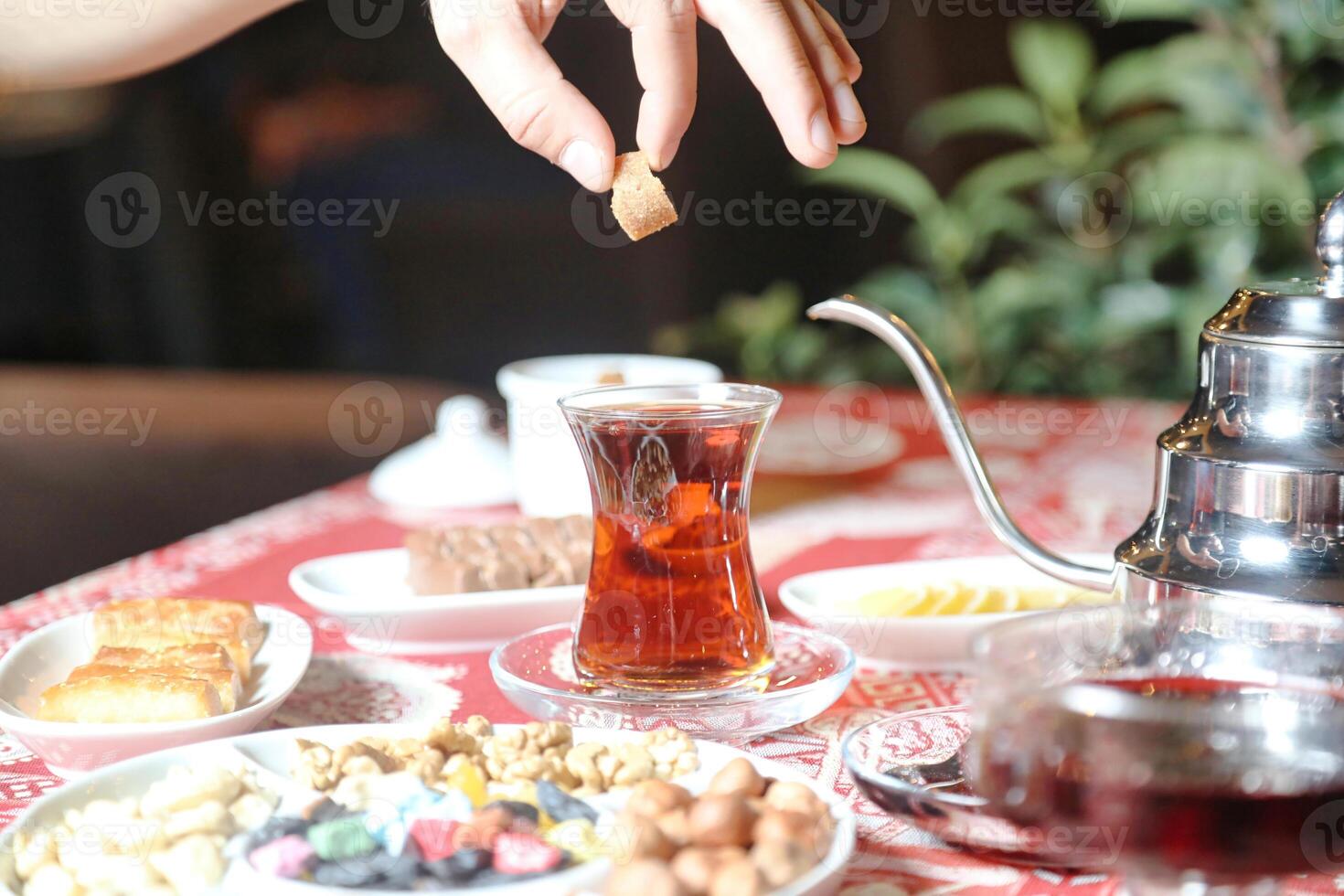 Person Gießen Tee in Keramik Teekanne foto