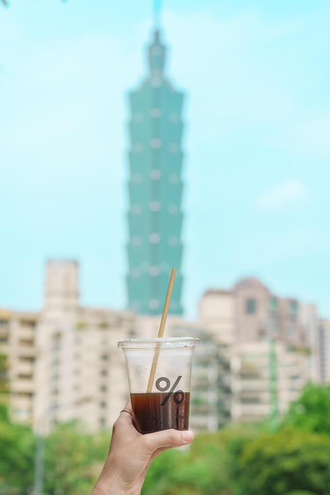 Frau Hand halten ein Glas von Arabica Kaffee gegen Taipeh Stadt Hintergrund. Taipeh, Taiwan, 05 April 2023 foto