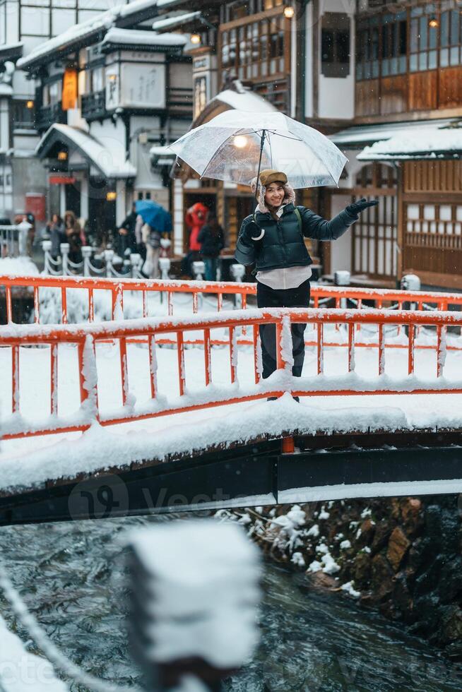 Frau Tourist Besuch Ginzan Onsen im Yamagata, glücklich Reisender Besichtigung japanisch Onsen Dorf mit Schnee im Winter Jahreszeit. Wahrzeichen und Beliebt zum Attraktion im Japan. Reise und Ferien Konzept foto