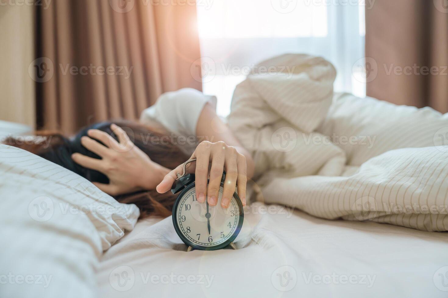 Alarm Uhr und asiatisch Frau Hand halt Zeit im Bett während Schlafen, jung Erwachsene weiblich aufwachen oben spät im das früh Morgen. entspannend , schläfrig, Täglich Routine und haben ein nett Tag Konzepte foto