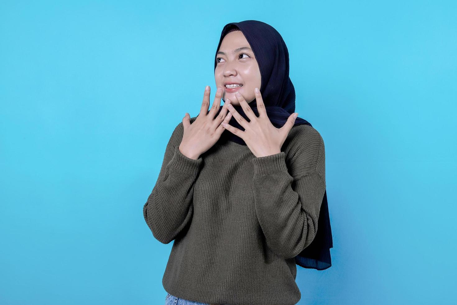 Nahaufnahme eines glücklichen Mädchens, das Hijab in Freizeitkleidung trägt und auf blauer Wand lächelt foto