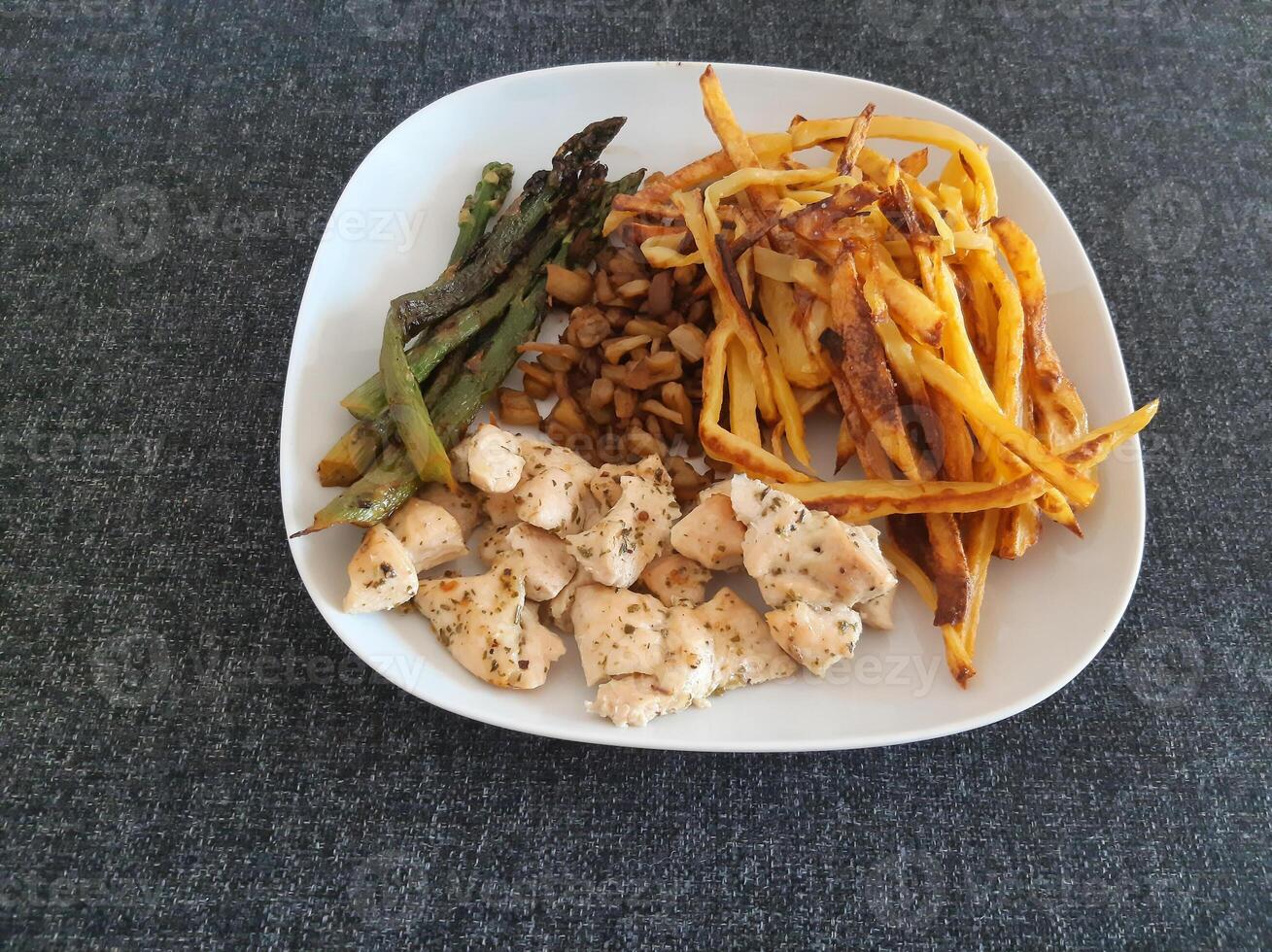 hausgemacht gegrillt Hähnchen mit Französisch Fritten, Aubergine und gegrillt Spargel, serviert auf ein Weiß Teller foto