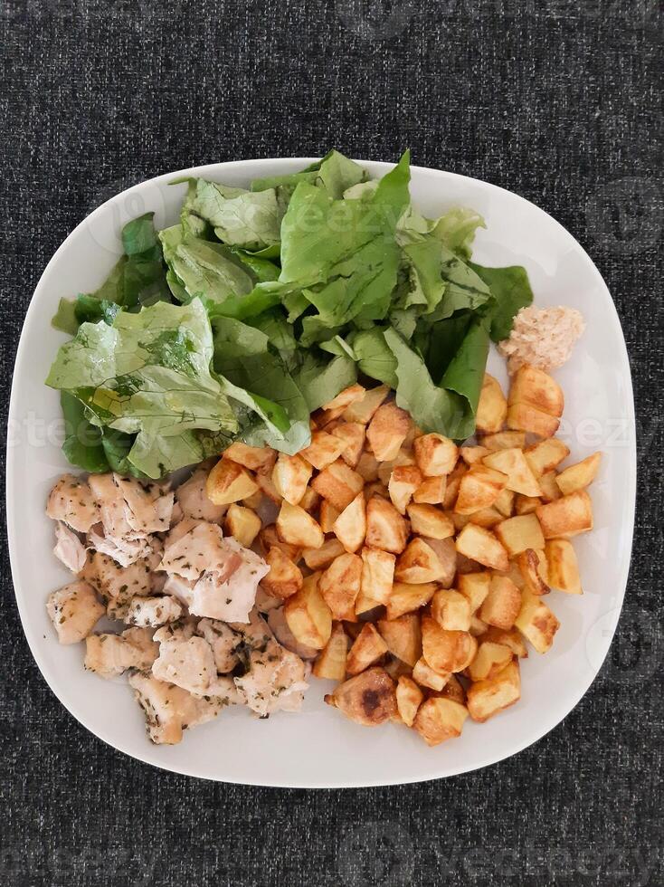 hausgemacht gegrillt Hähnchen mit Französisch Fritten und Grün Salat, serviert auf ein Weiß Teller foto