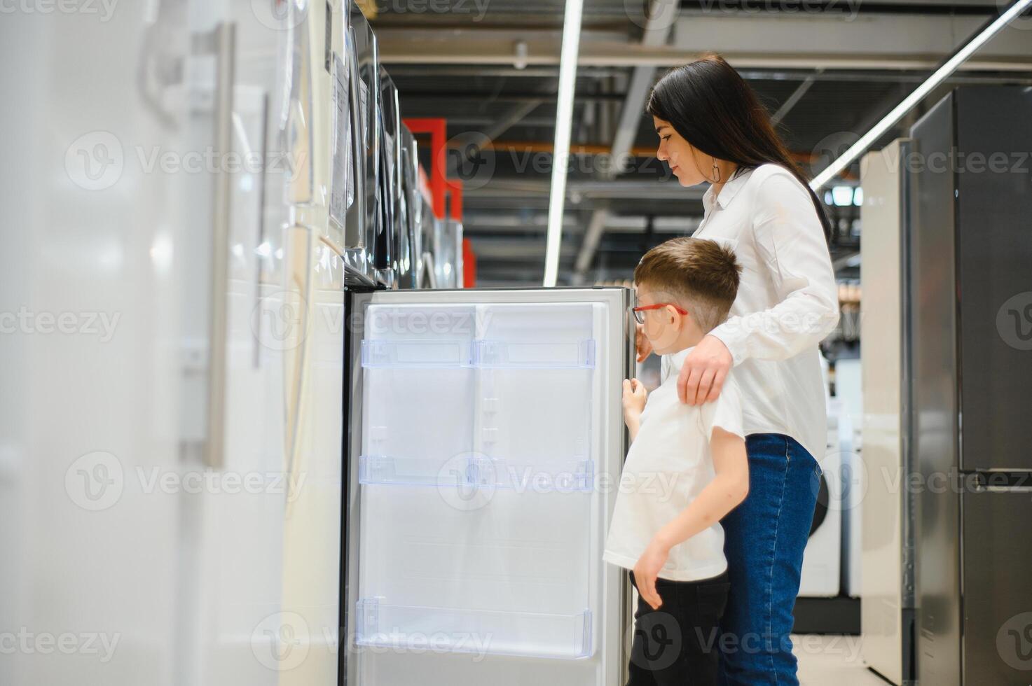 glücklich Mutter mit Sohn wählen Kühlschrank im Zuhause Gerät Geschäft foto