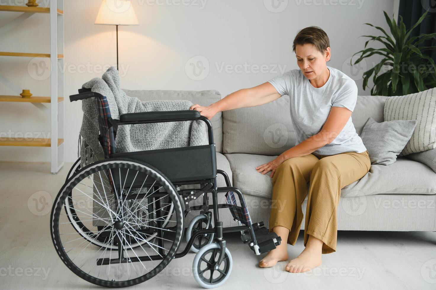 Senior Frau versuchen zu sitzen Nieder im Rollstuhl von Couch foto