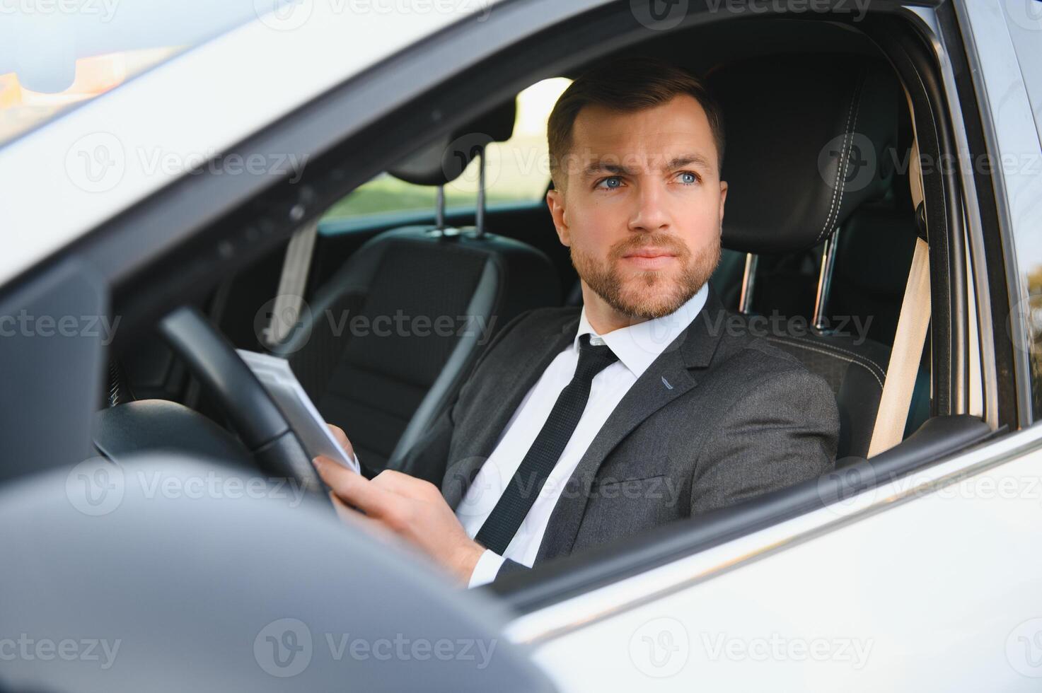 Mann mit Stil und Status. hübscher junger Mann im vollen Anzug, der beim Autofahren lächelt foto