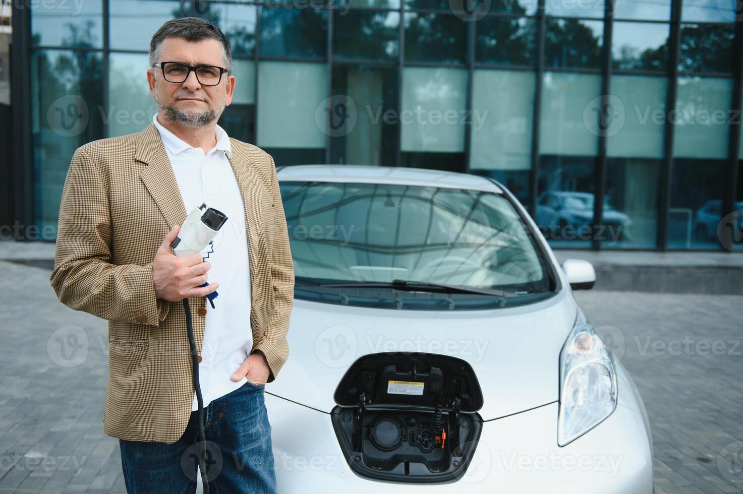 Mann Gebühren ein elektrisch Auto beim das Laden Bahnhof foto