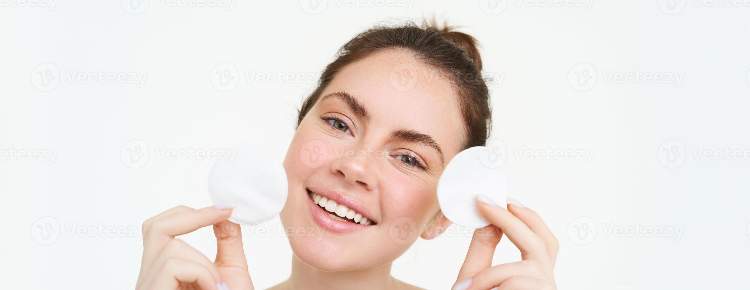 Porträt von jung Frau Reinigung ihr Gesicht, nimmt aus ihr bilden, Waschen ihr Gesicht, mit Hautpflege Routine mit Baumwolle Pads, isoliert Über Weiß Hintergrund foto