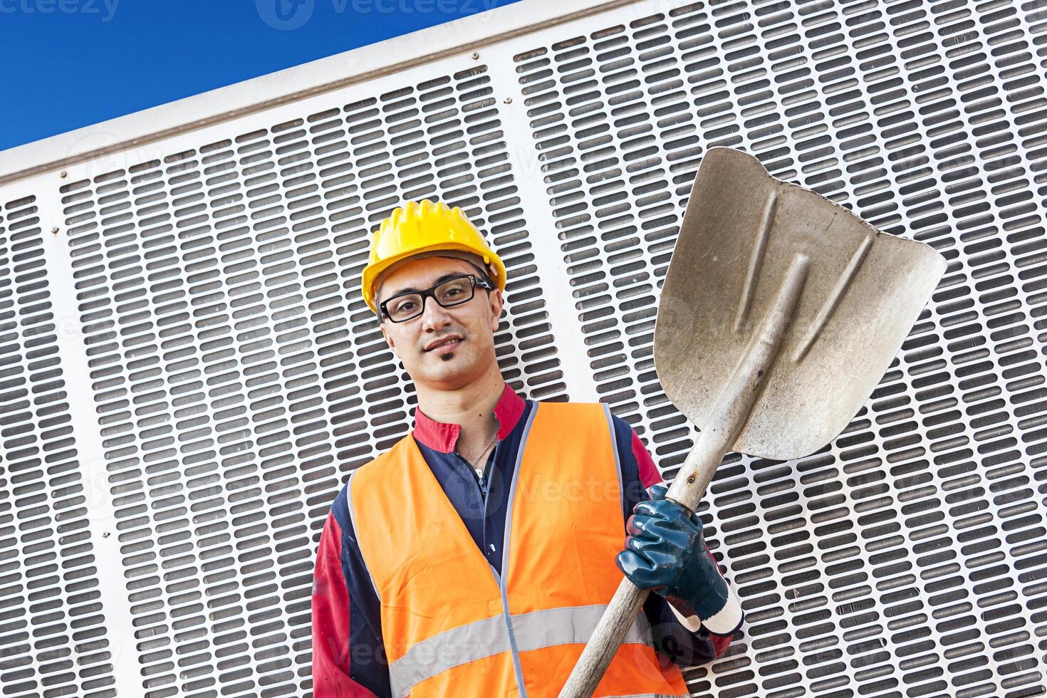 Porträt von ein jung Ingenieur tragen ein Helm gegen Metall Hintergrund foto