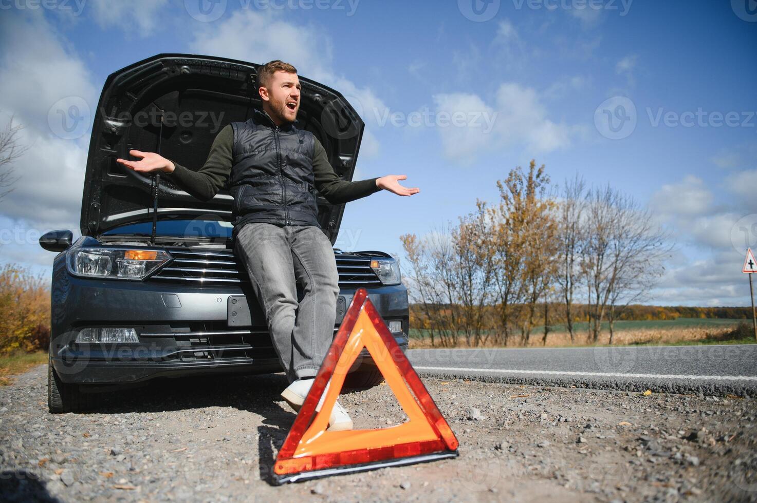 gut aussehend jung Mann mit seine Auto gebrochen Nieder durch das Straßenrand foto