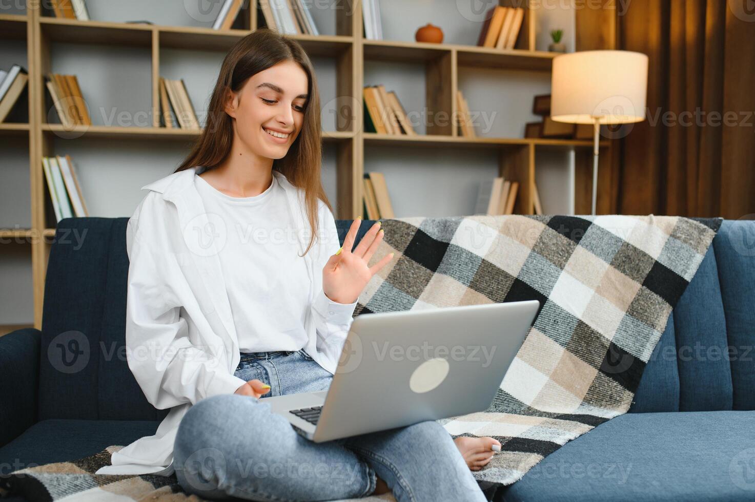 lächelnd attraktiv jung Frau Sitzung auf Sofa mit Laptop kommunizieren Arbeiten online beim heim, glücklich Teen Mädchen Tippen auf Computer, genießen Schreiben Blog oder chatten mit freunde im Sozial Netzwerk foto