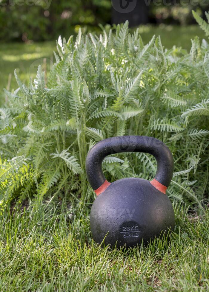 schwer Eisen Kettlebell auf Grün Gras im ein Hinterhof - - draussen Fitness Konzept foto