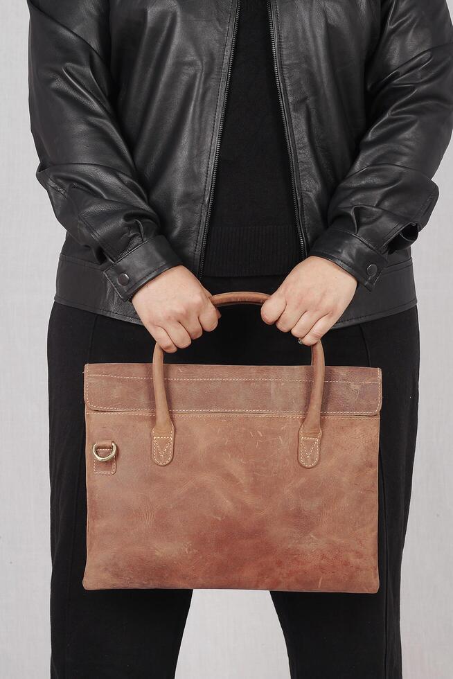 ein Frau im ein schwarz Leder Jacke und schwarz Hose mit braun Leder Hand Tasche foto