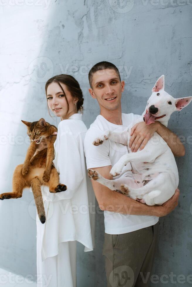 jung Paar Kerl und Mädchen im ein hell Zimmer spielen mit Haustiere foto