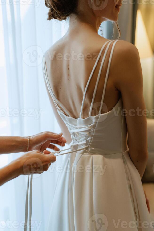 Vorbereitungen für die Braut mit dem Anziehen des Hochzeitskleides foto