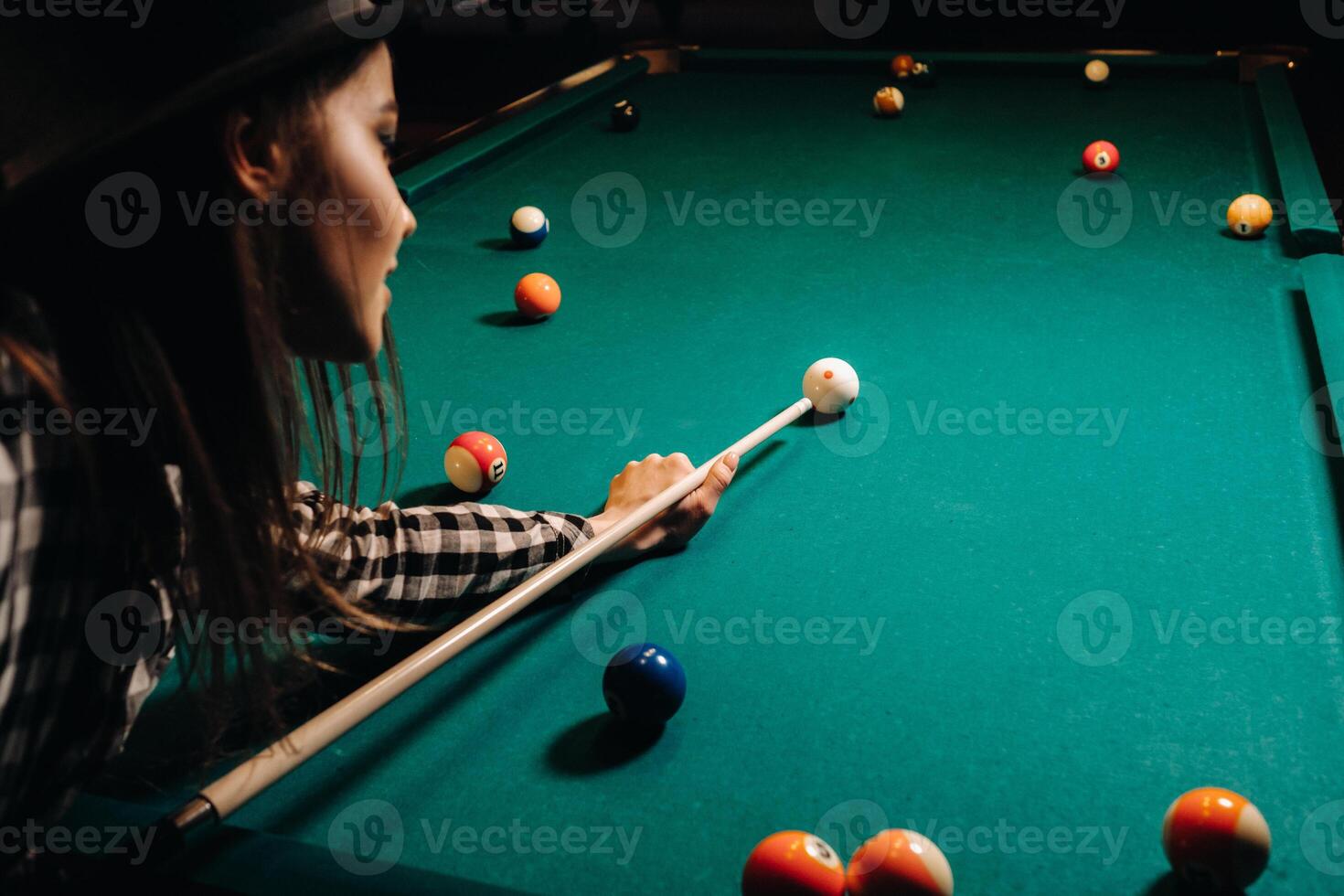 ein Mädchen im ein Hut im ein Billard- Verein mit ein Stichwort im ihr Hände Treffer ein Ball.spielen Billard foto