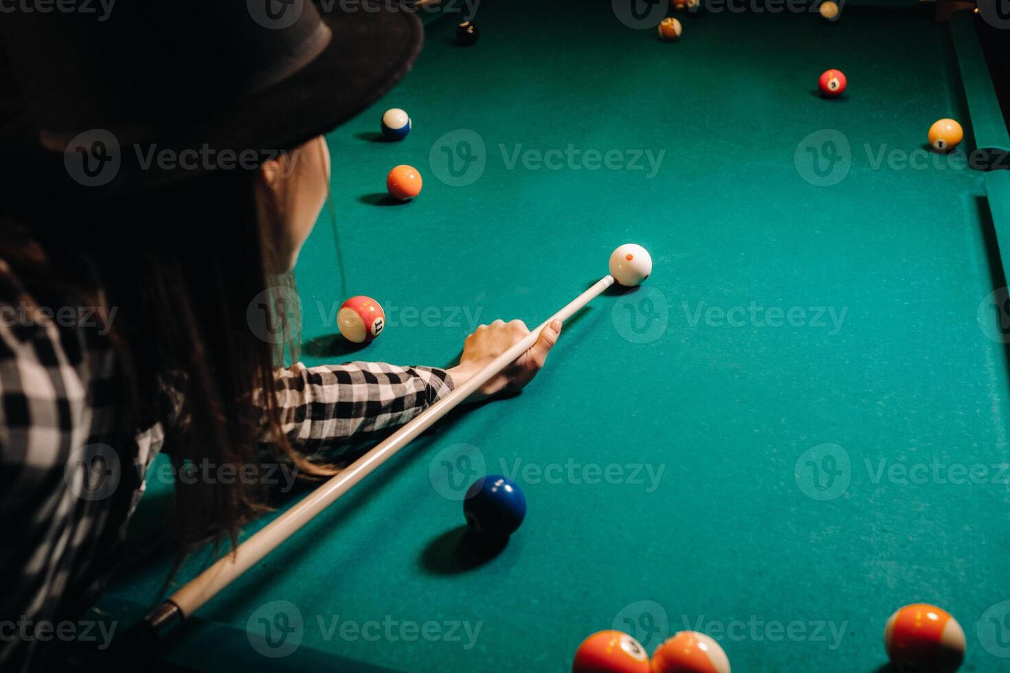 ein Mädchen im ein Hut im ein Billard- Verein mit ein Stichwort im ihr Hände Treffer ein Ball.spielen Schwimmbad foto