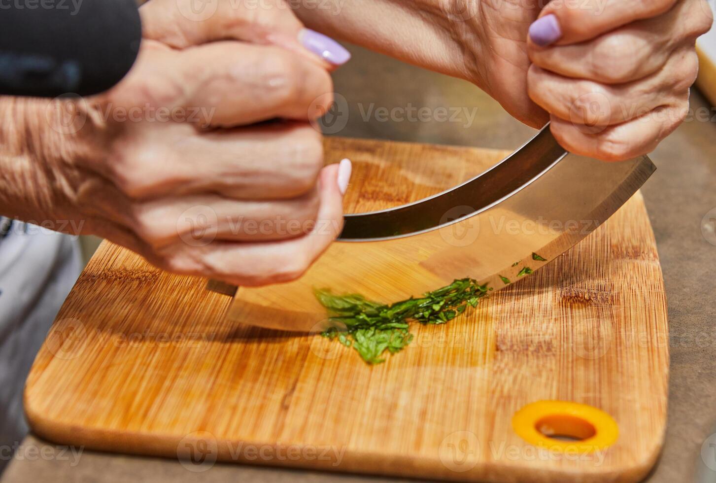 Hände Hacken Grün Zwiebel mit Mezzaluna auf hölzern Schneiden Tafel im hausgemacht Küche foto