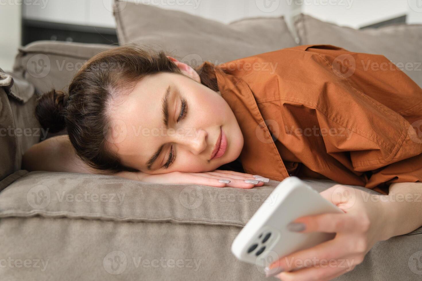 schließen oben Porträt von ruhen Frau, Lügen auf Couch beim heim, lesen Nachrichten auf Smartphone, Scrollen Sozial Medien App auf Handy, Mobiltelefon Telefon und entspannend auf Sofa foto