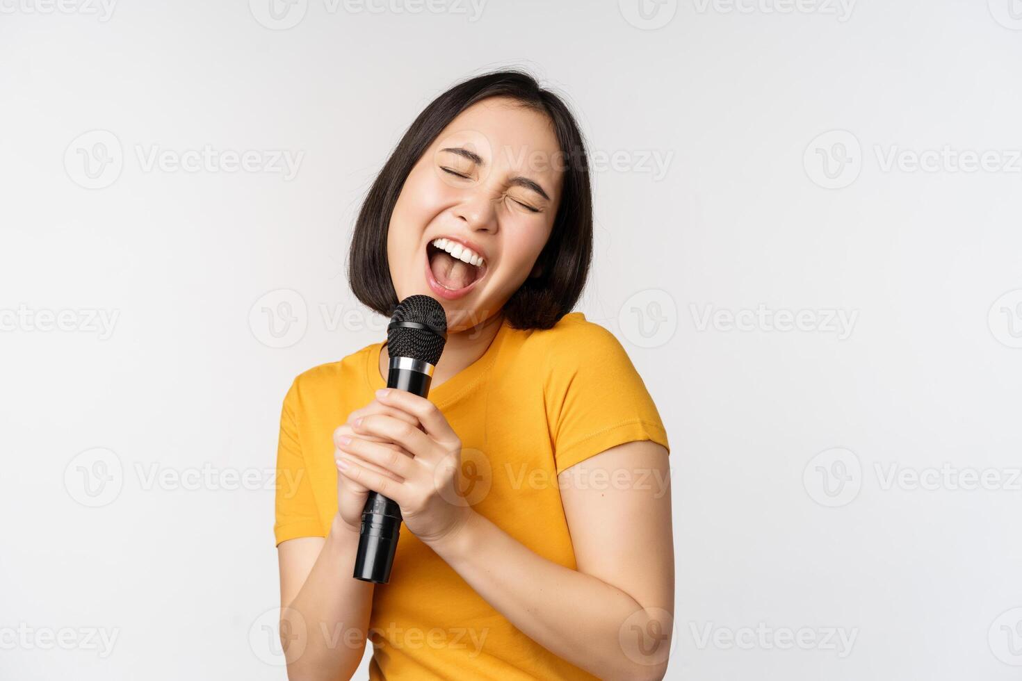 glücklich asiatisch Mädchen Tanzen und Singen Karaoke, halten Mikrofon im Hand, haben Spaß, Stehen Über Weiß Hintergrund foto