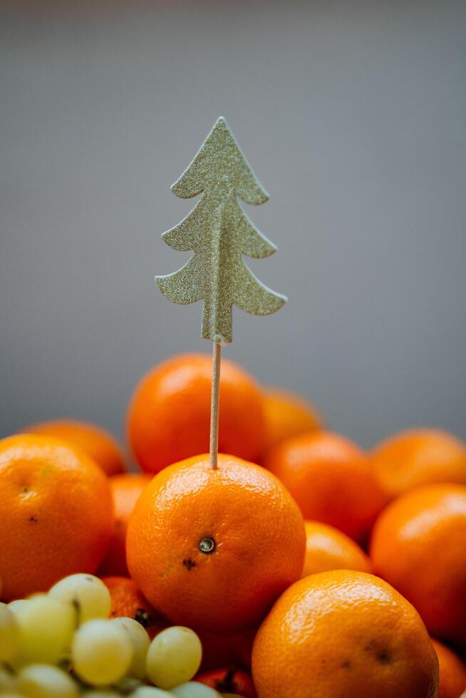 das golden Weihnachten Baum Dekoration ist stecken im das Mandarine. natbrmort zum das Neu Jahr. Dekoration zum das festlich Tisch. Kunst Foto, Minimalismus foto