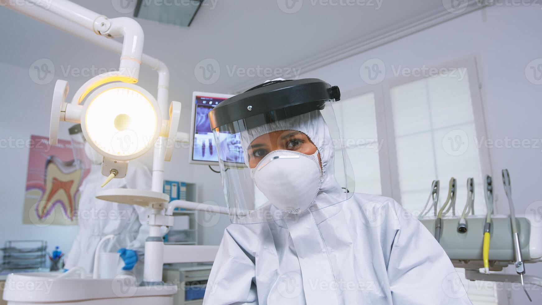 geduldig pov von Zahnarzt erklären Zähne Behandlung tragen covid schützend passen im Neu normal stomatologisch Büro. stomatologe im Sicherheit Ausrüstung gegen Coronavirus während Wärmepflege prüfen von geduldig. foto