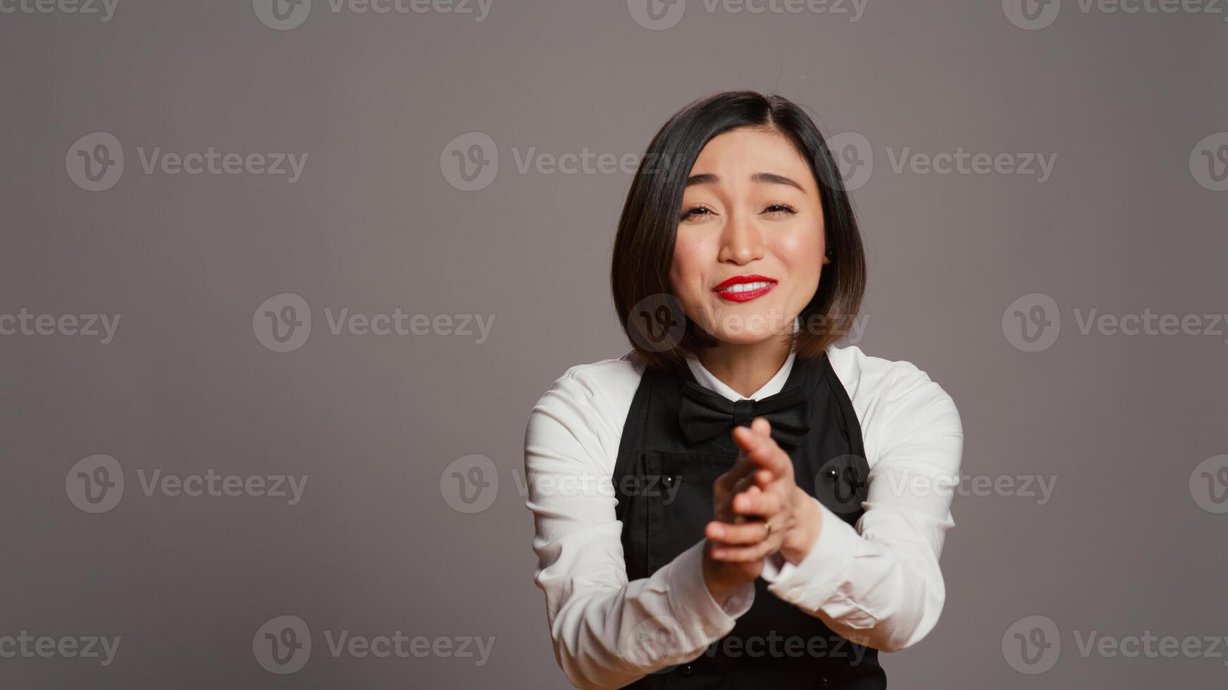 Restaurant Hostess klatschen Hände und feiern zum jemand, Jubel und Sprichwort Herzliche Glückwünsche im Studio. asiatisch Kellnerin mit Uniform und Schürze applaudieren ein Person, Anerkennung. Kamera b. foto