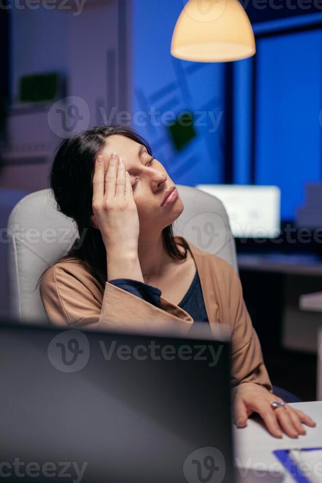 müde Geschäftsfrau behalten Augen geschlossen Reiben Stirn weil anstrengend. Mitarbeiter fallen schlafend während Arbeiten spät beim Nacht allein im das Büro zum wichtig Unternehmen Projekt. foto