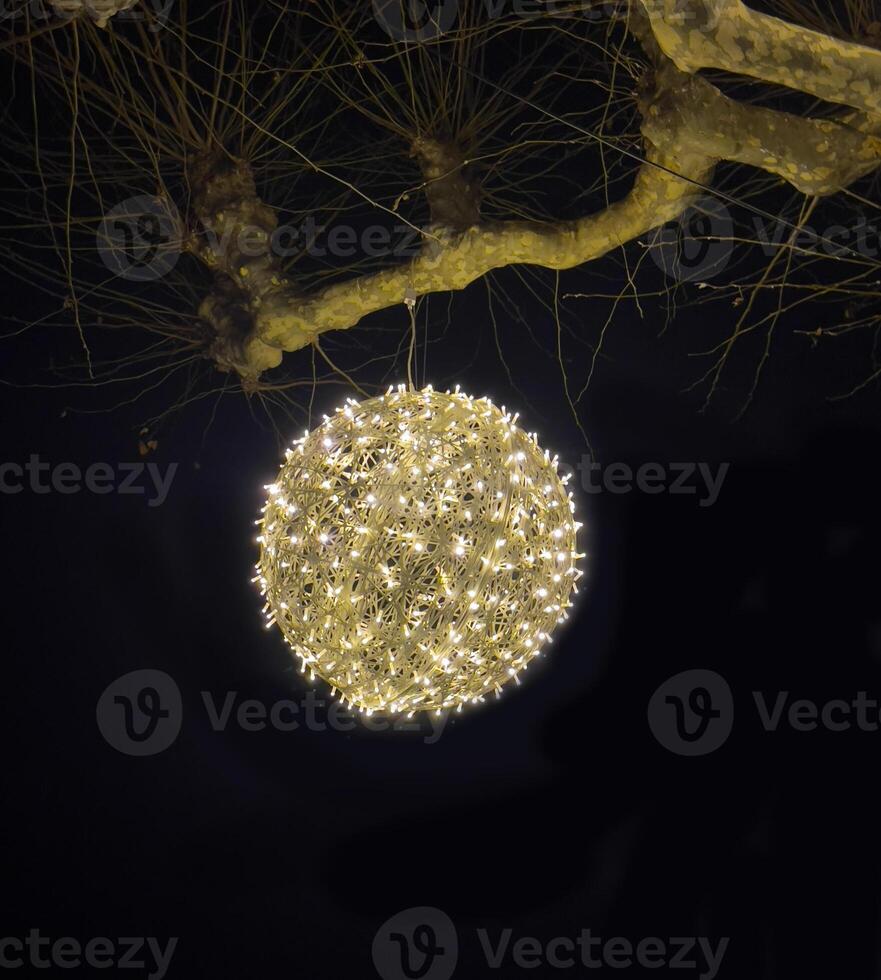 ein beleuchtet Ball hängend von ein Baum Ast foto