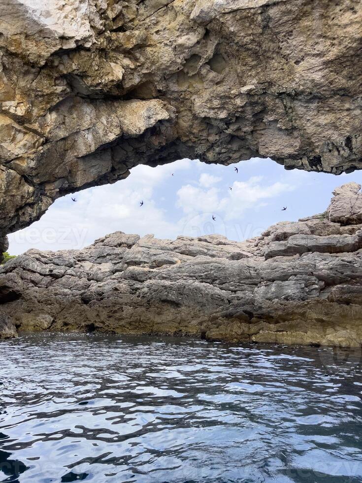 ein groß Felsen Formation mit Vögel fliegend aus von es foto